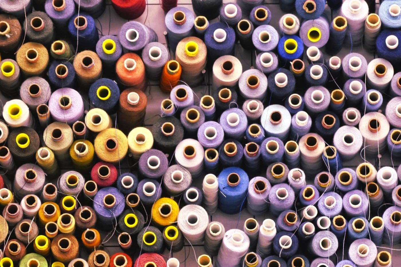 A wall of colourful thread spools in a textile workshop