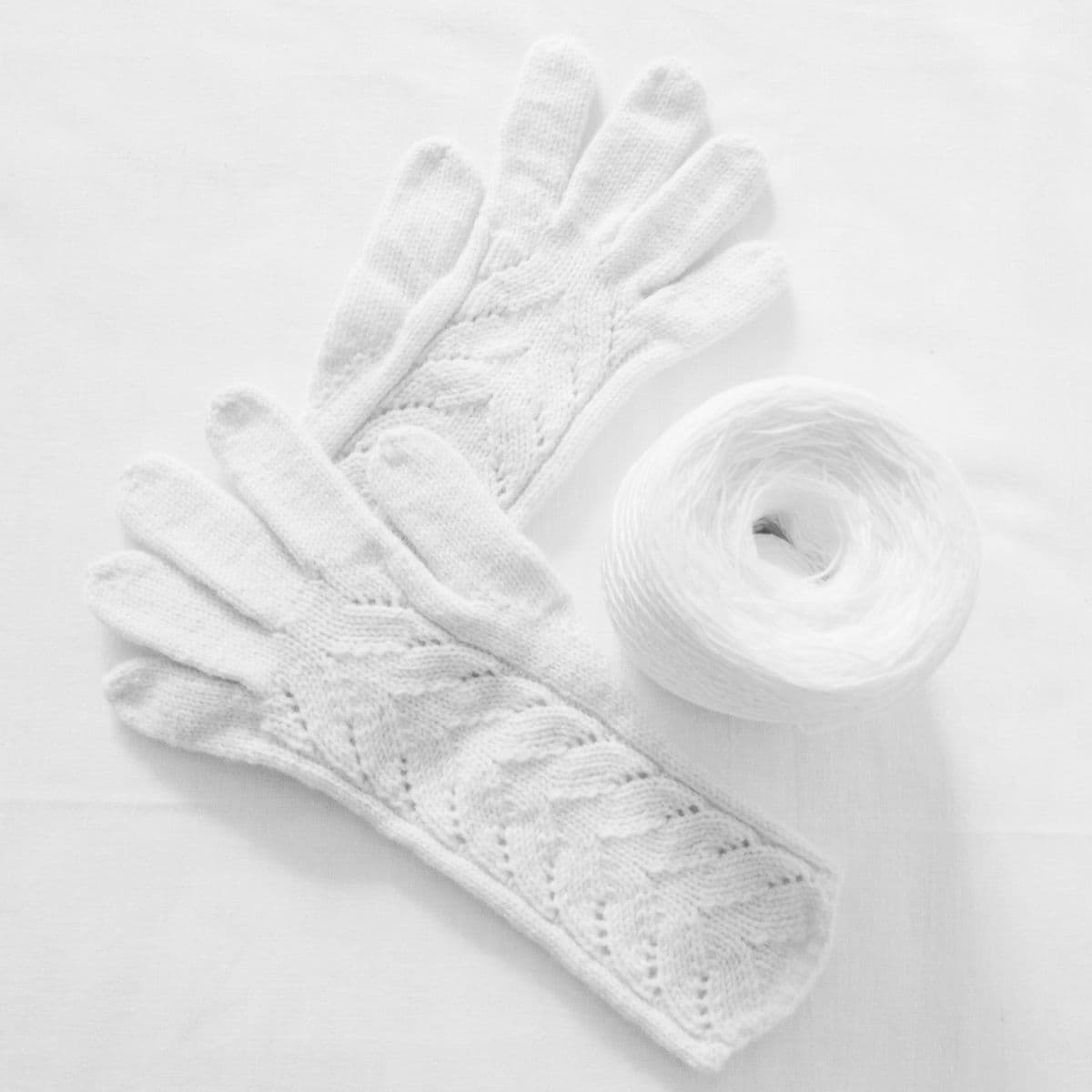 White lace-knit gloves on white linen