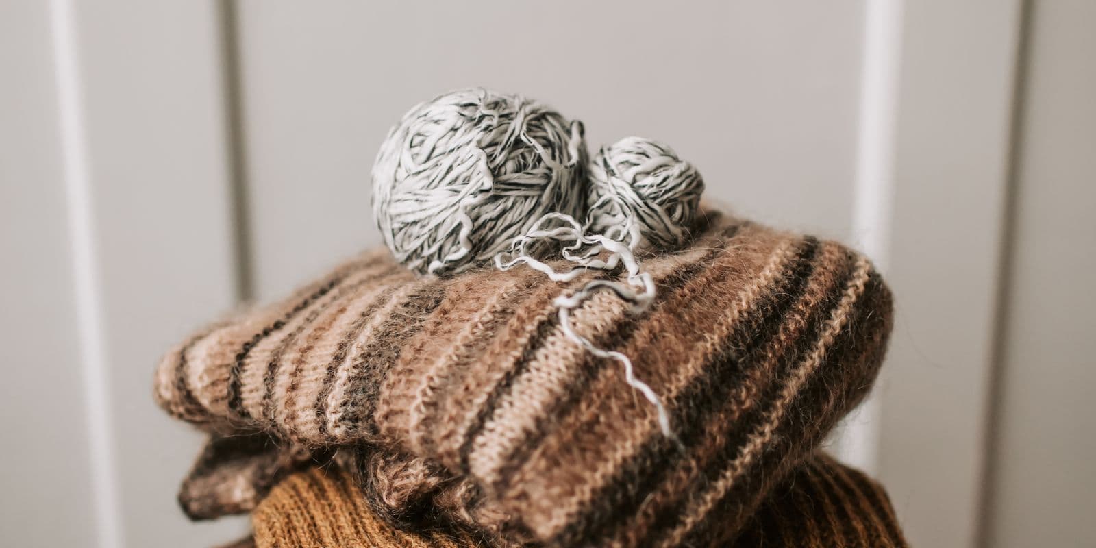 A stack of folded ribbed knit scarves with yarn