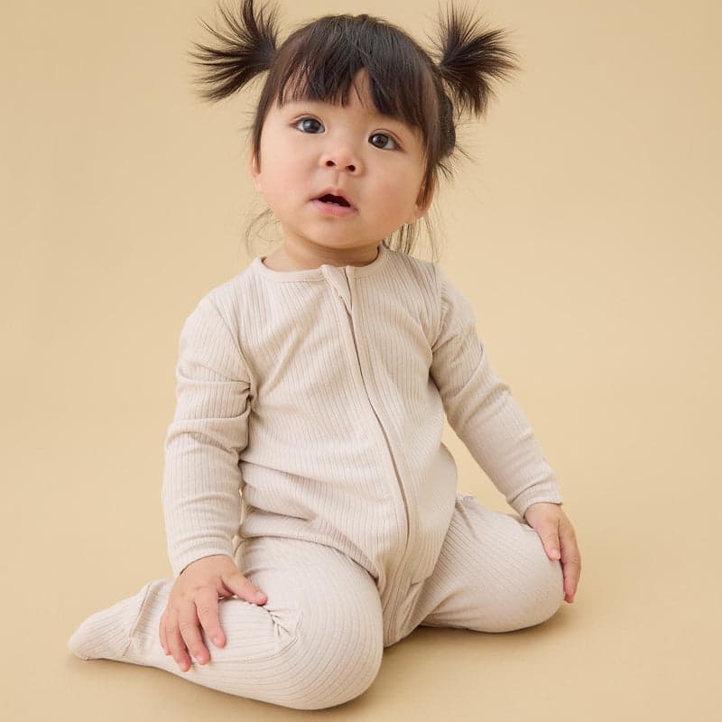 A baby in a ribbed ecru sleepsuit