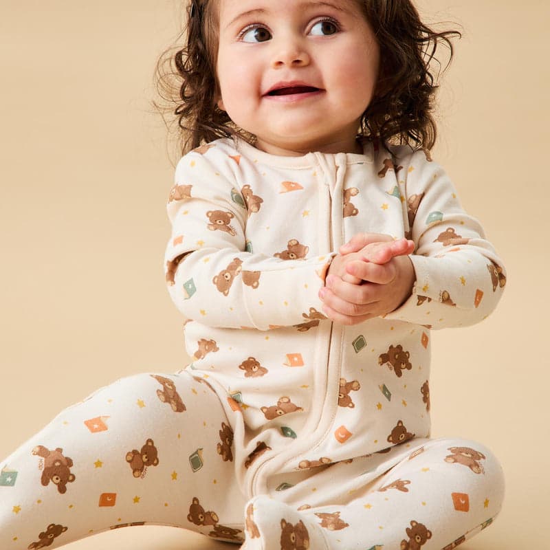 A baby in a cream teddy-print sleepsuit