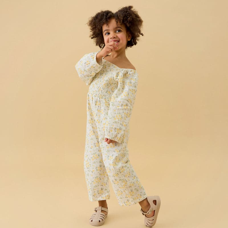 A child in a cream floral muslin jumpsuit