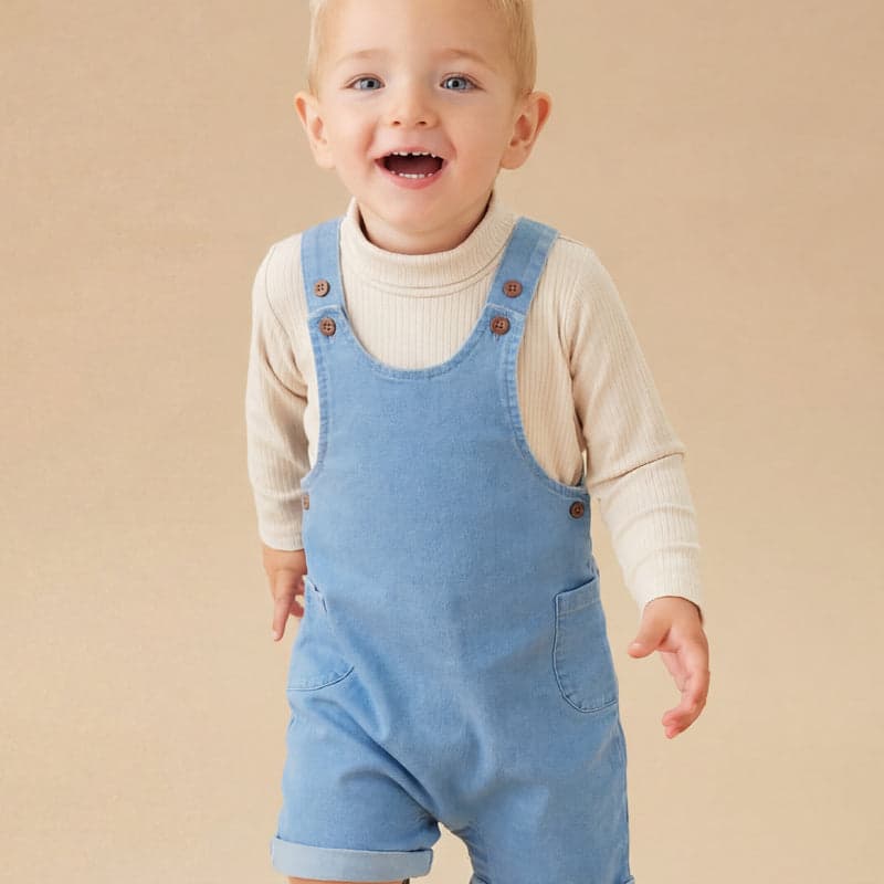 A boy in light denim dungarees and cream top