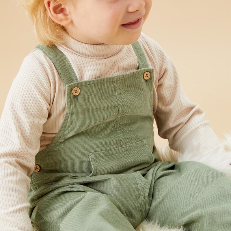 A toddler in sage corduroy dungarees