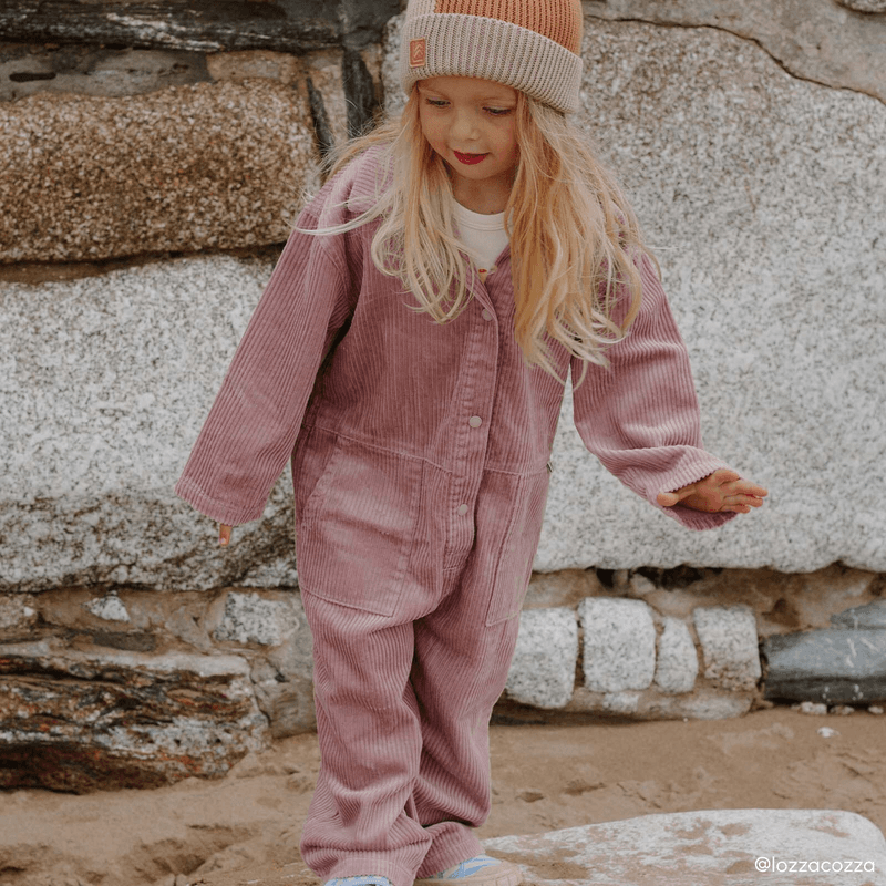 A girl in a dusty pink corduroy jumpsuit