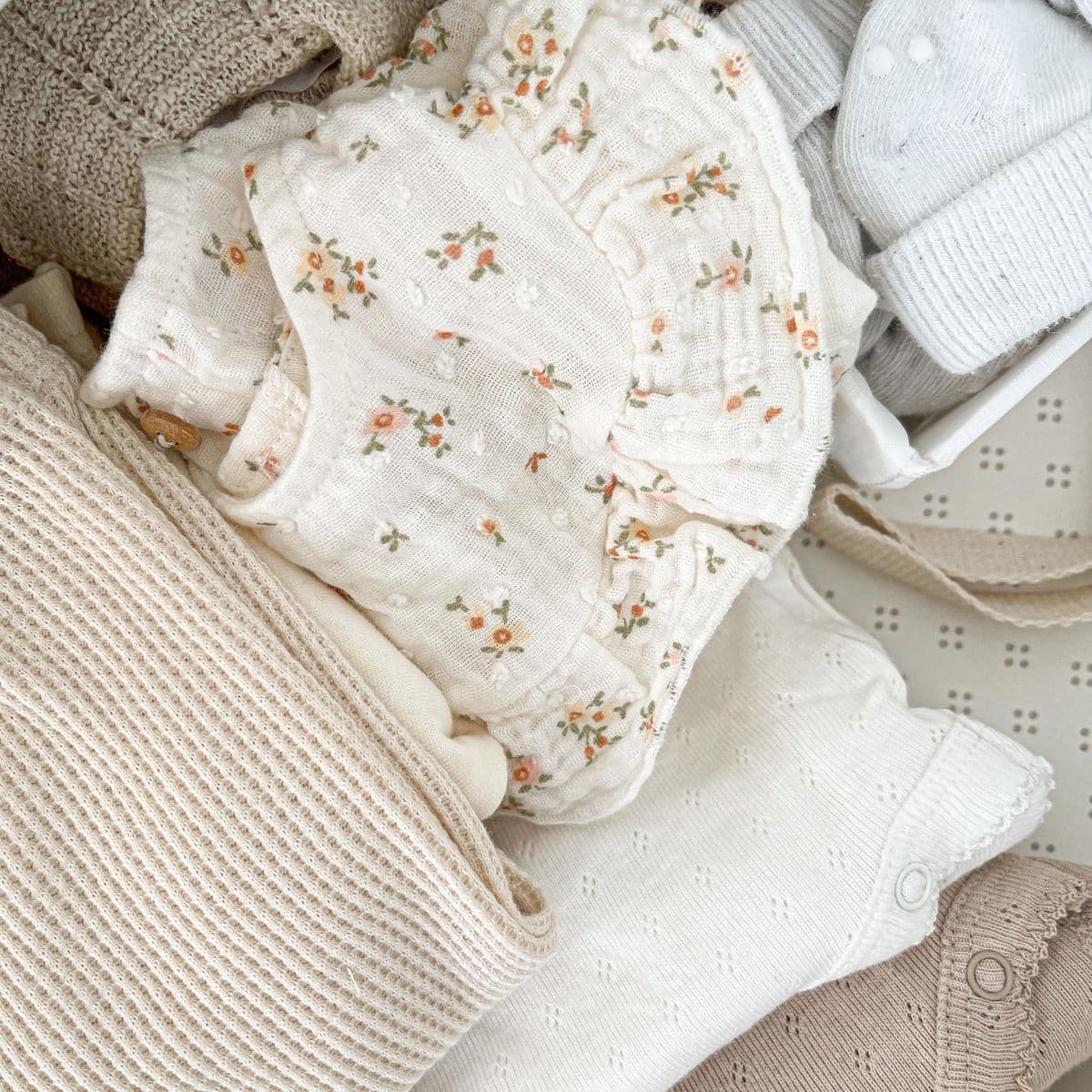 A flat-lay of folded neutral baby clothes