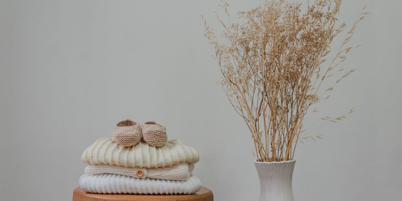 Knitted baby booties on a stack of folded baby knits