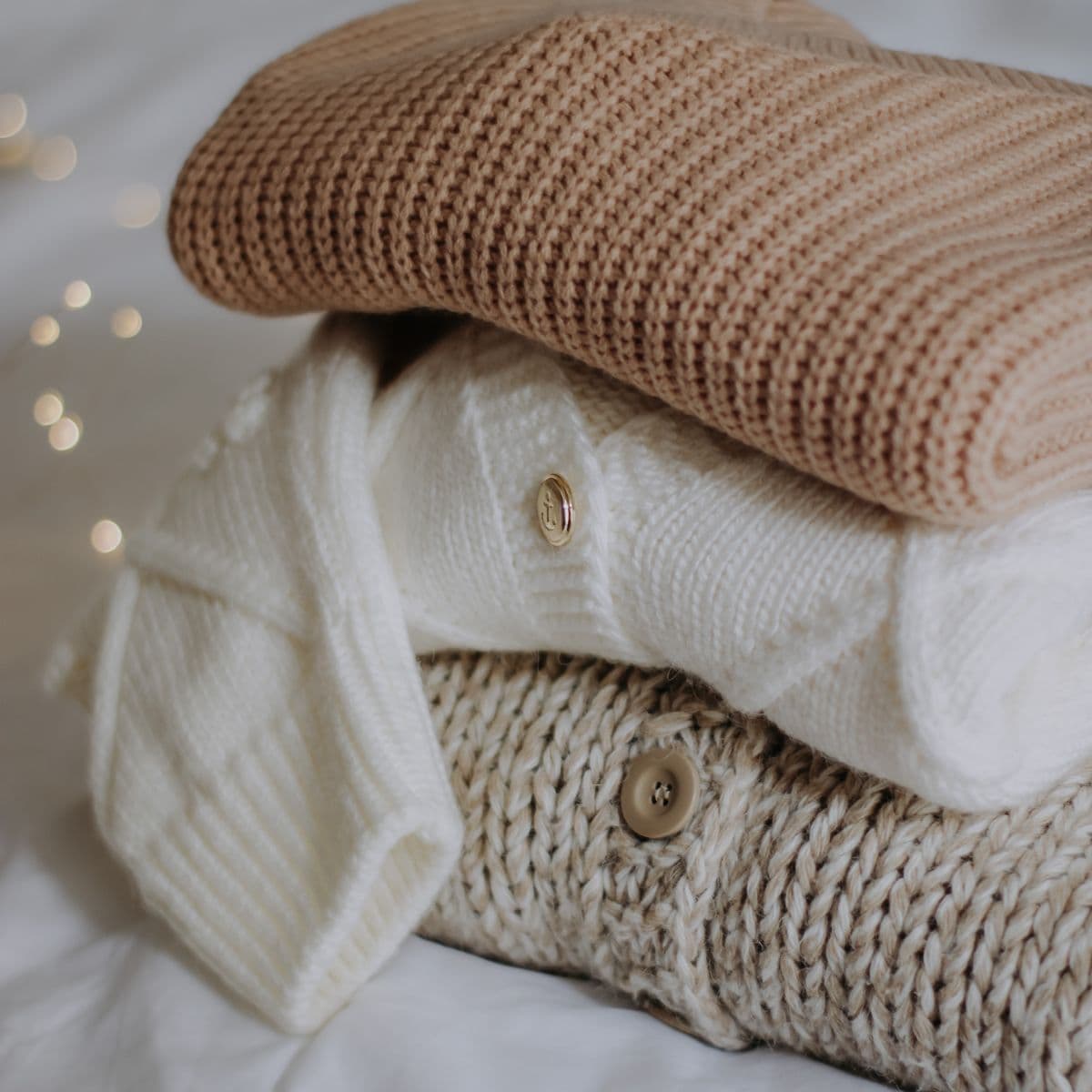 Folded camel and cream knit baby cardigans with wooden buttons