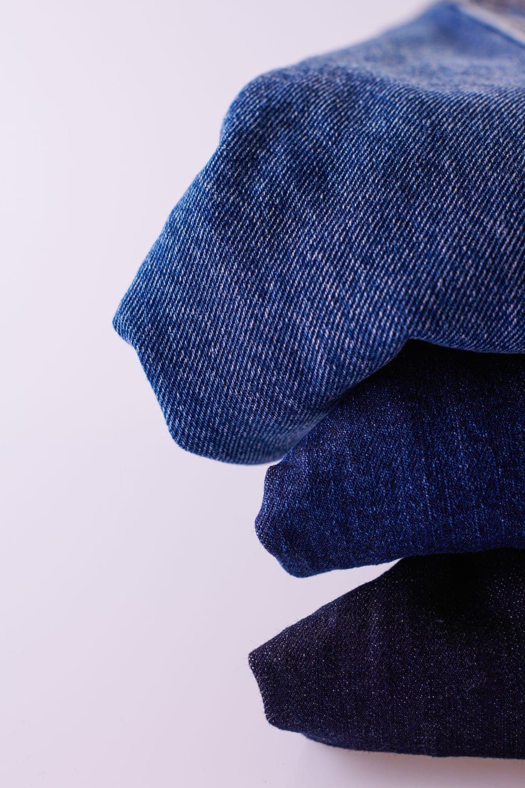 Folded denim jeans on a soft pink background