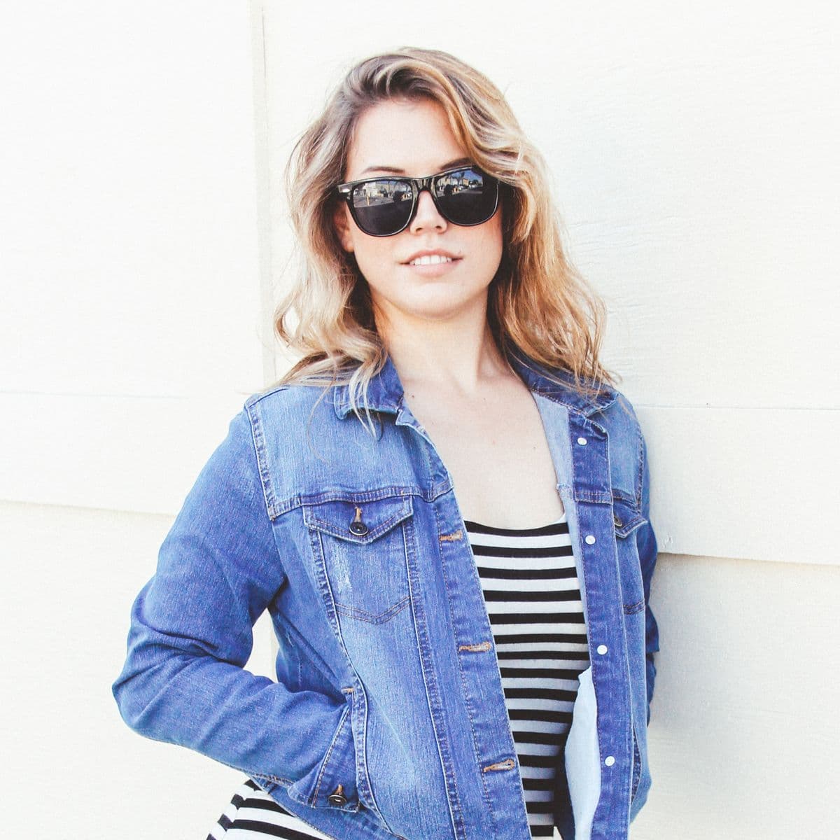 Woman in a mid-wash denim jacket over a striped top