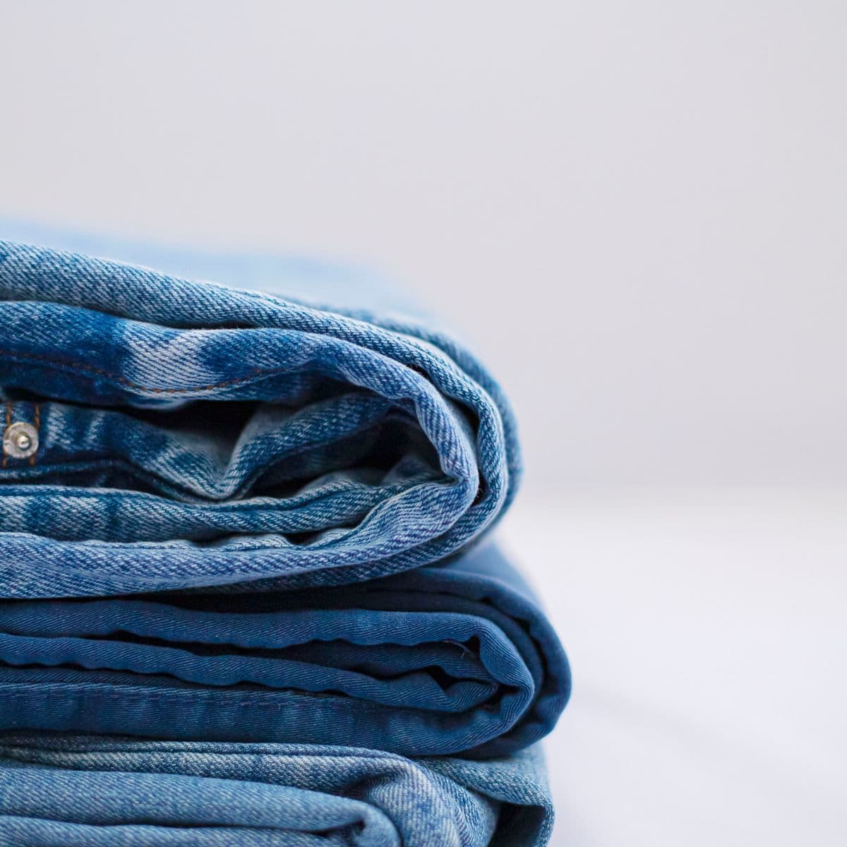 A small stack of folded light-wash denim