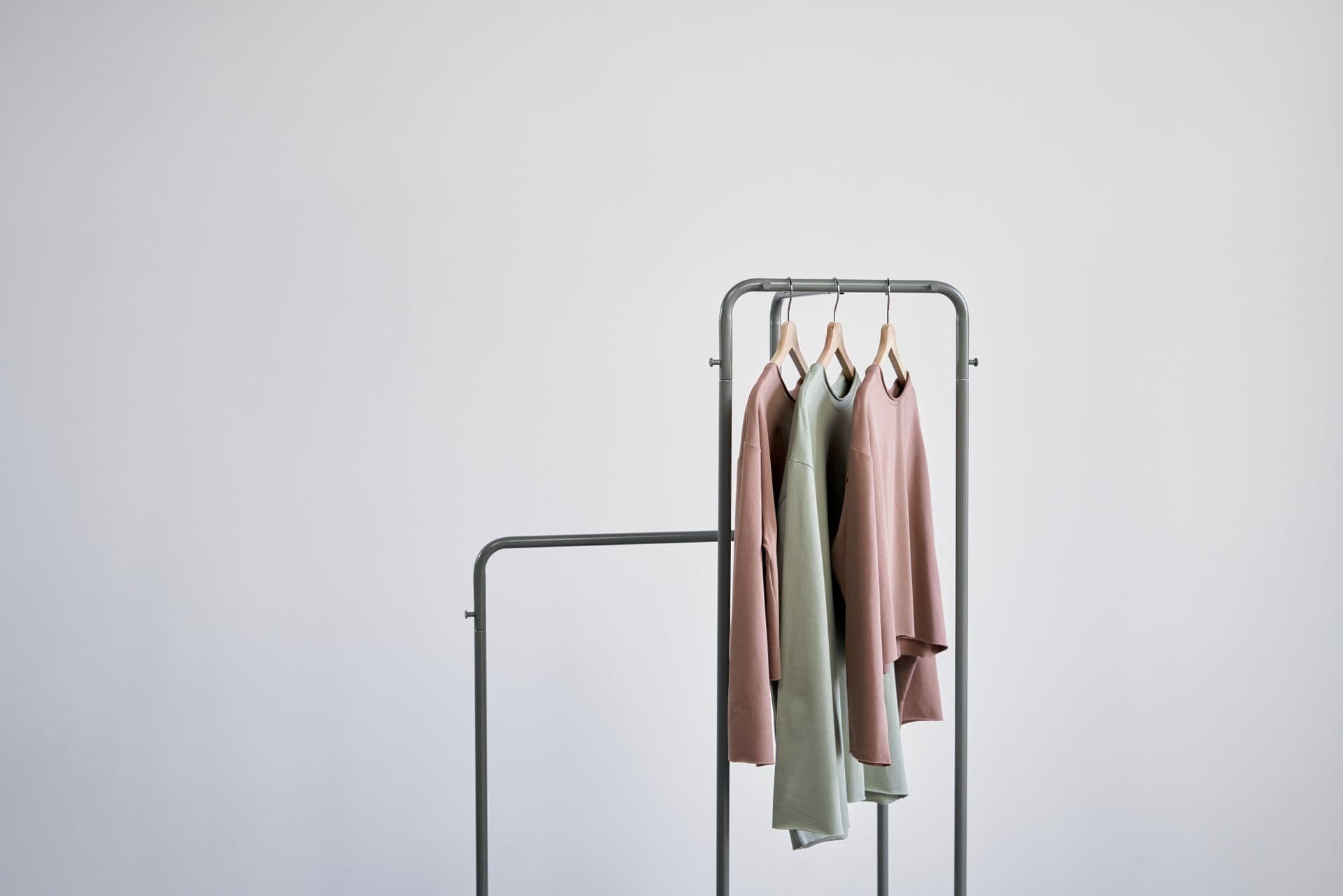 Soft neutral garments on a minimal clothing rail in a bright, airy studio
