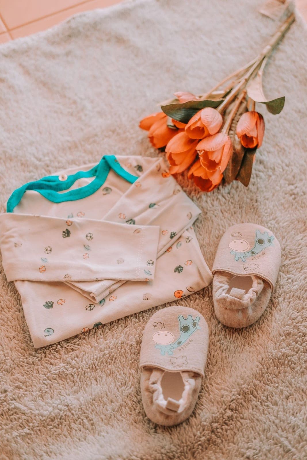 A neutral baby-clothing flat lay with flowers