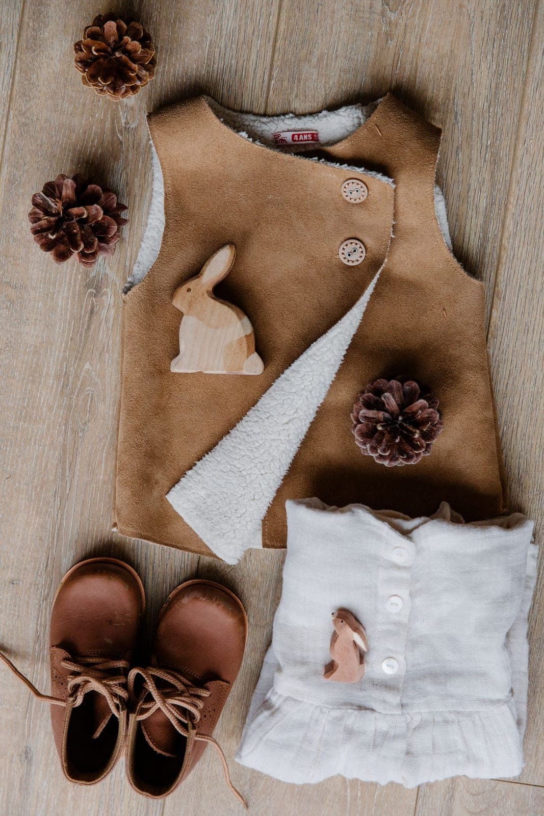 A folded beige baby onesie and accessories