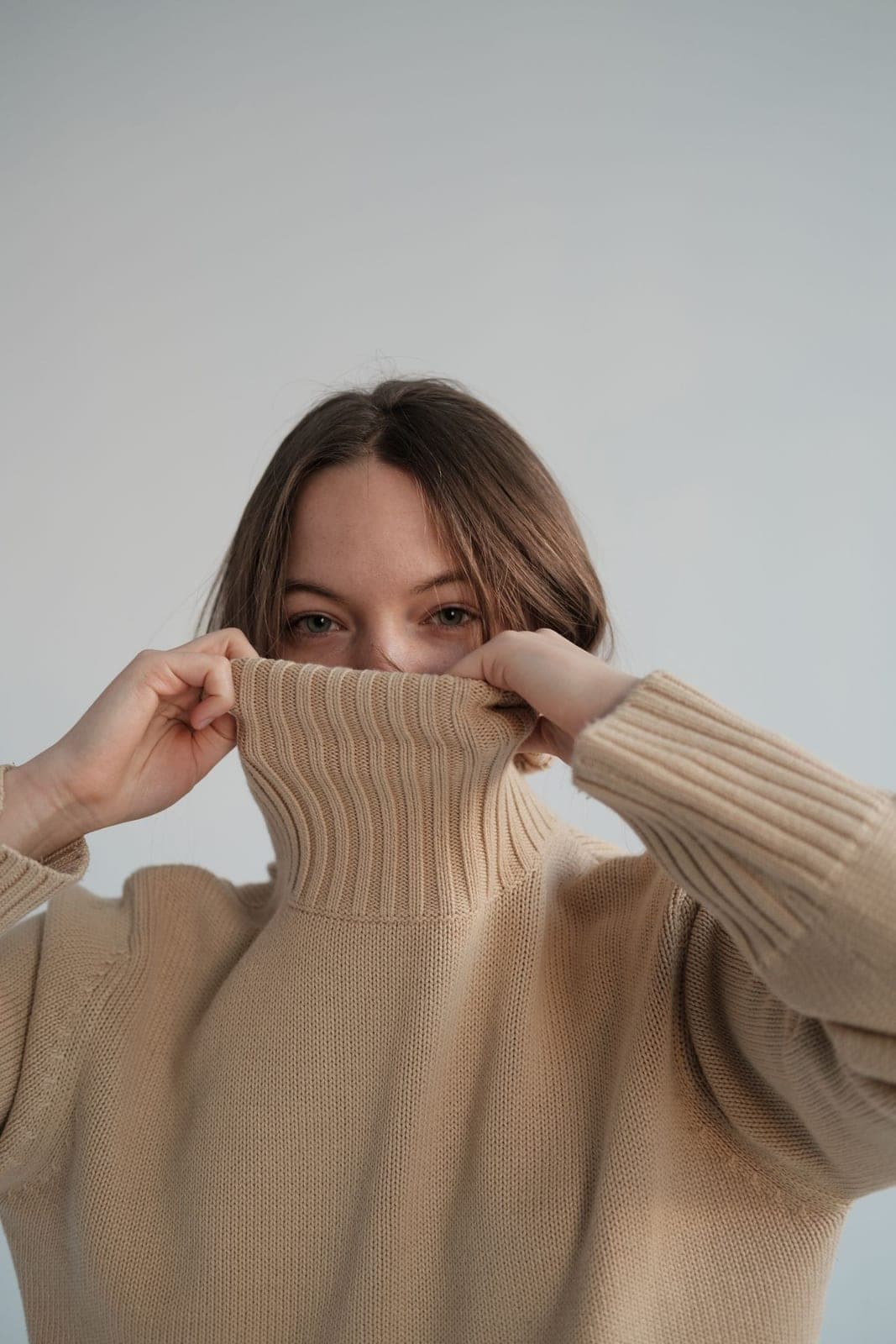 A model in a soft, neutral-toned knitted sweater