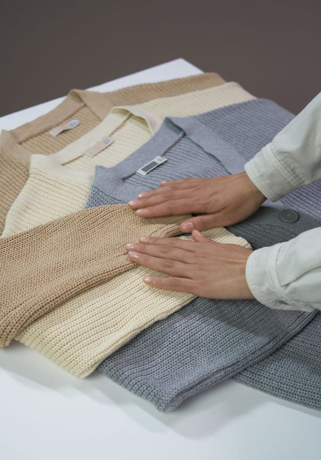Neutral knitted sweaters being folded
