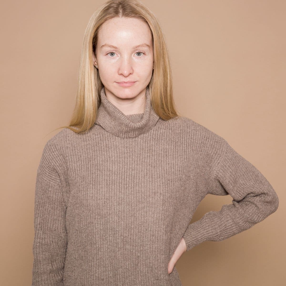 Model in a soft taupe ribbed turtleneck