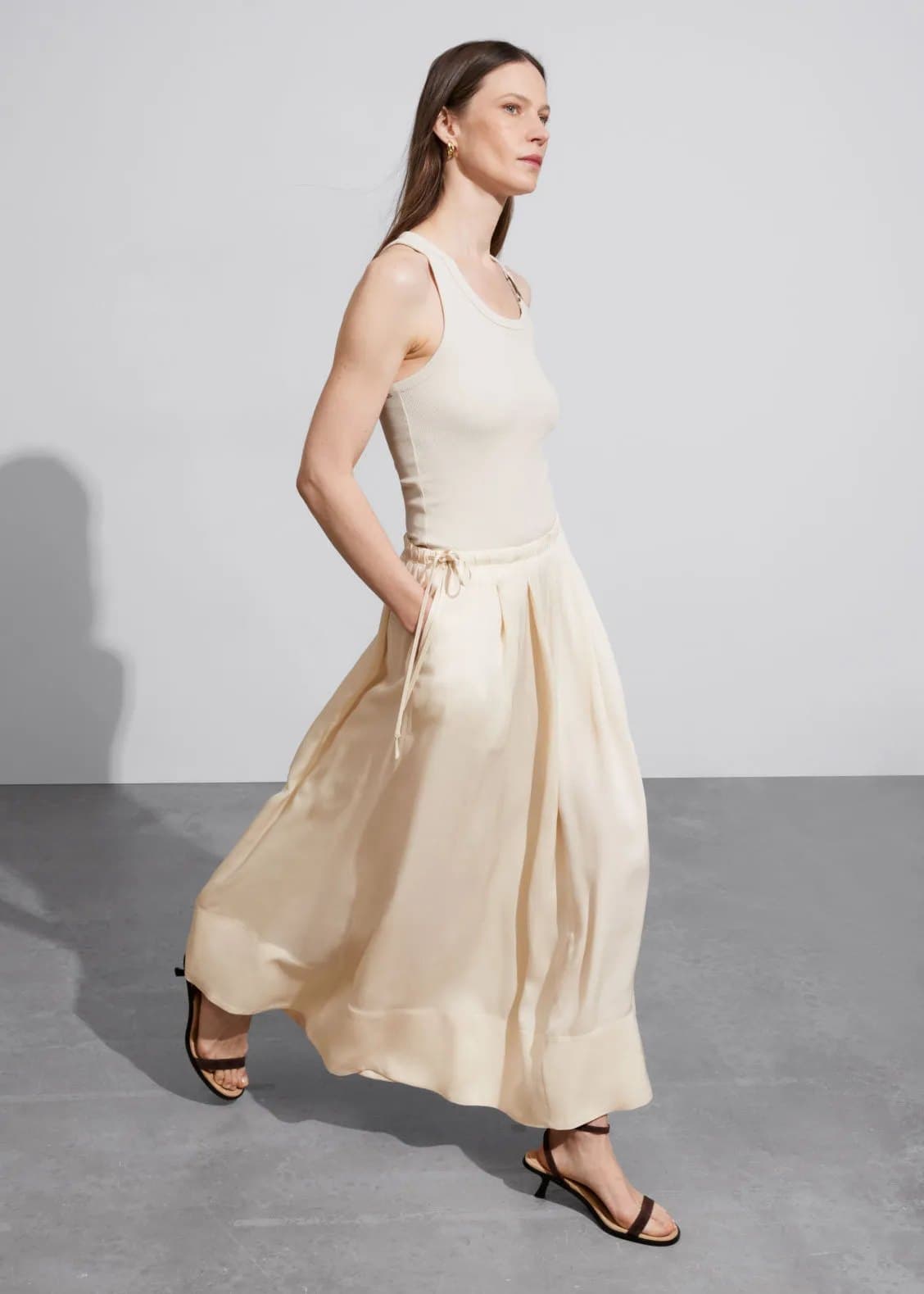 Model in a flowing cream satin maxi skirt