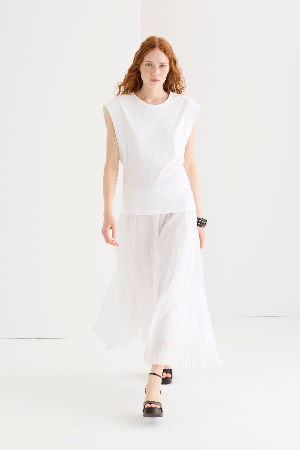 Model in a sheer white pleated maxi skirt