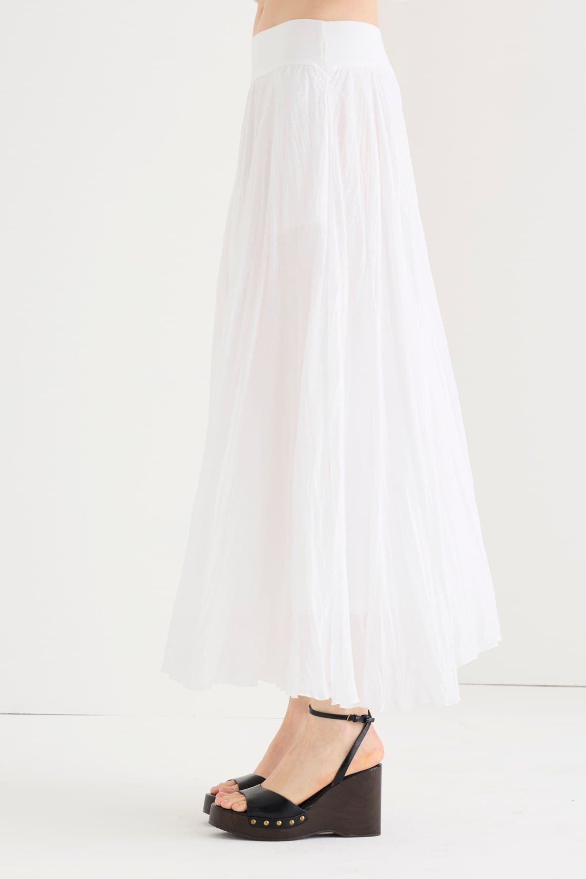 Detail of a white crinkle-pleated maxi skirt