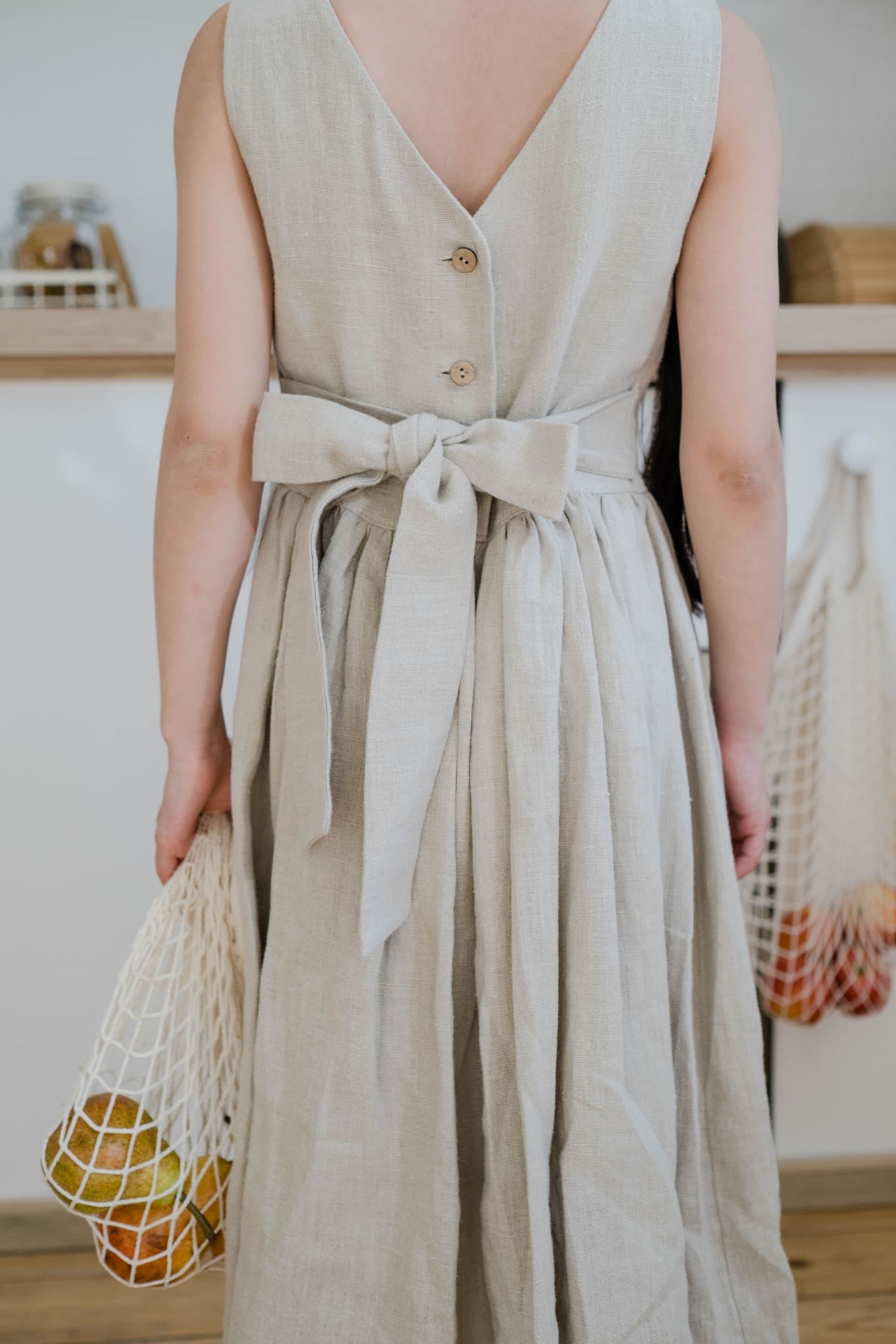 A model in a soft natural linen dress with a back-tie bow