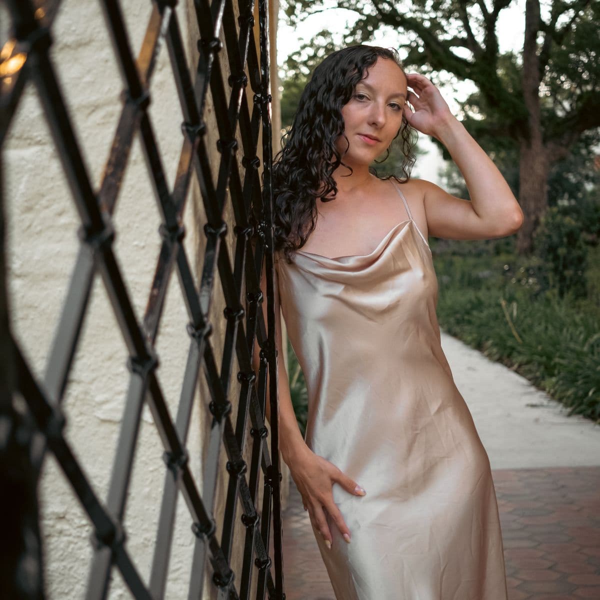Woman in a champagne satin slip dress in soft outdoor light