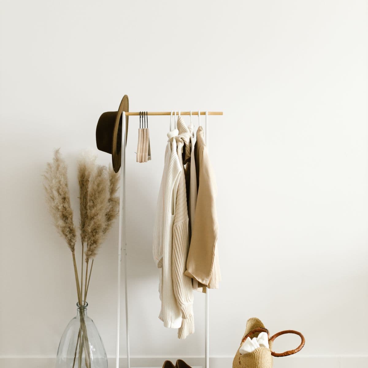 A styled rack with a cream knit, hat and pampas