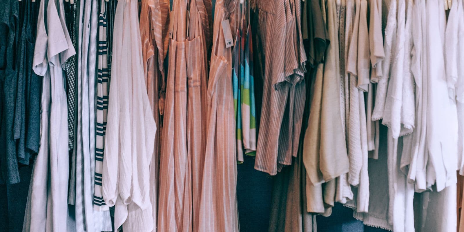 A wide rail of neutral dresses in stone and blush