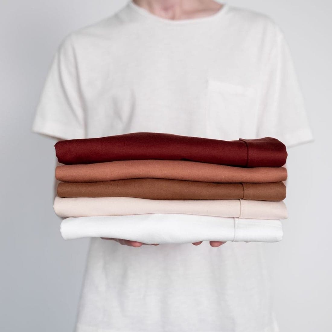 A neat stack of freshly folded shirts in soft neutral tones