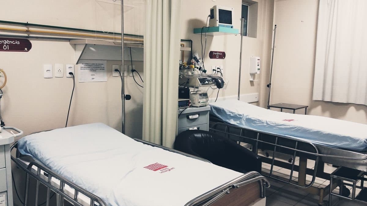 Two made-up hospital beds with white sheeting