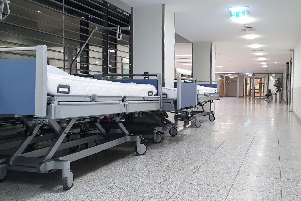 A line of hospital beds with white bedding
