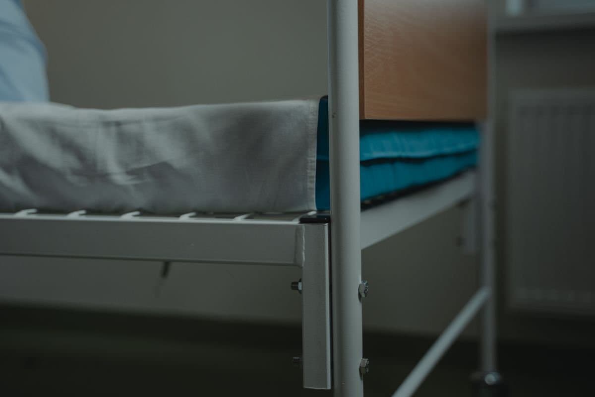 A hospital bed base with a fresh mattress