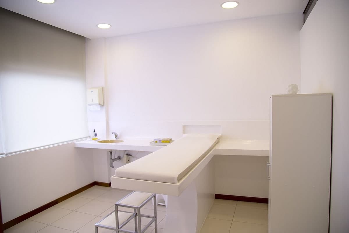 A sunlit hospital ward bed with a white pillow