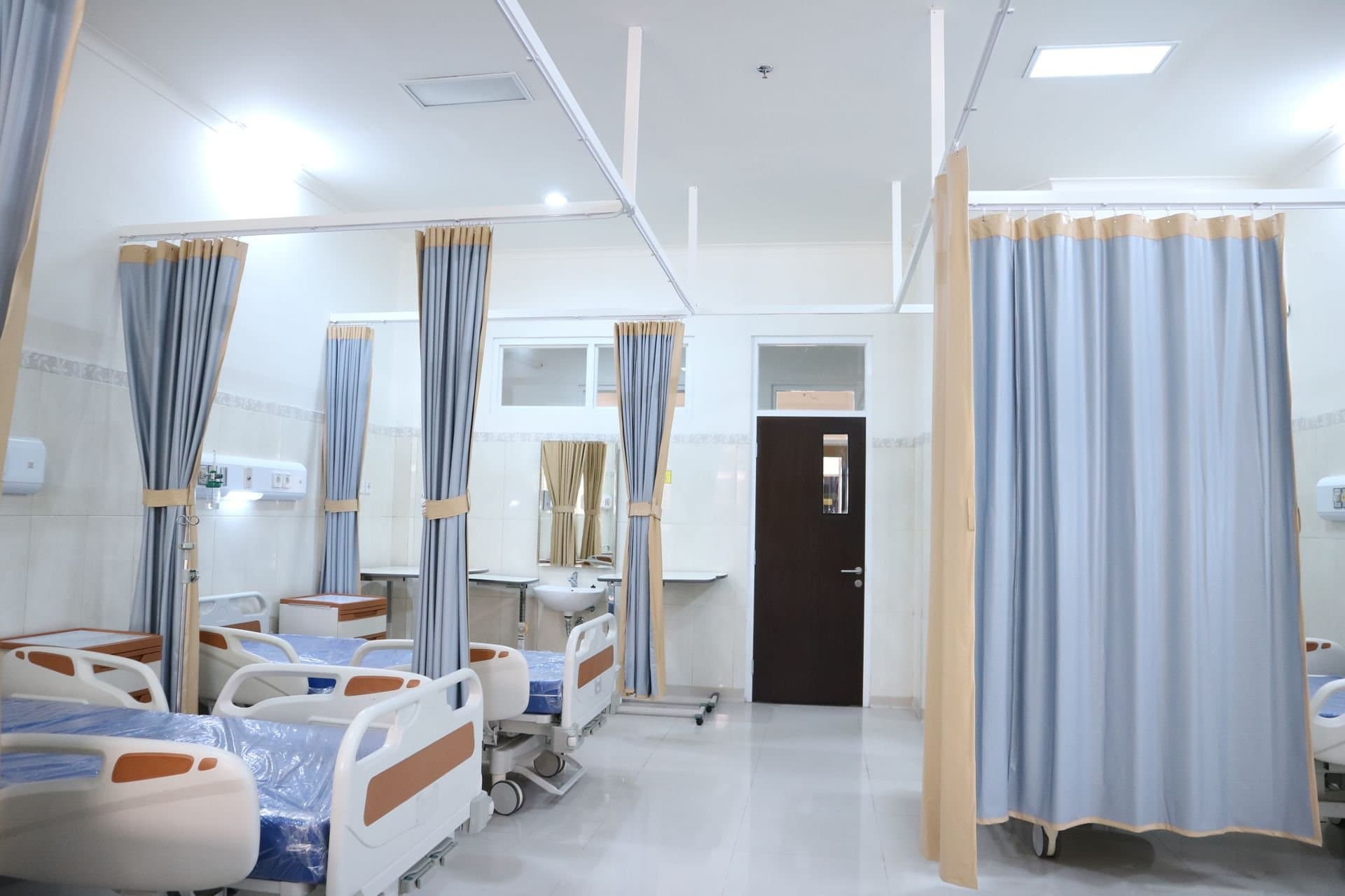 A hospital ward with curtained bays and beds dressed in clean linen
