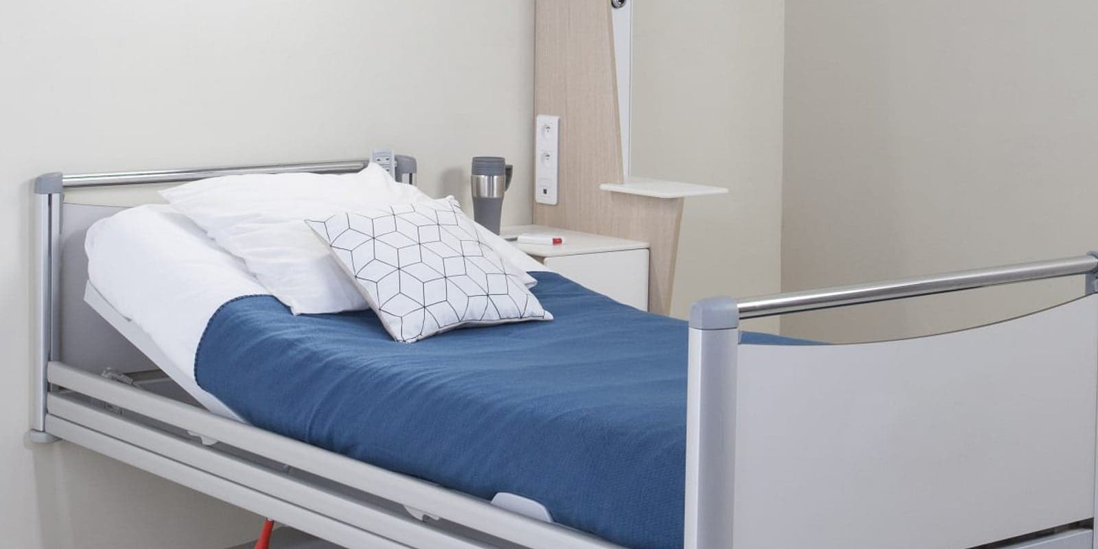 A hospital bed with a navy blanket and white linen