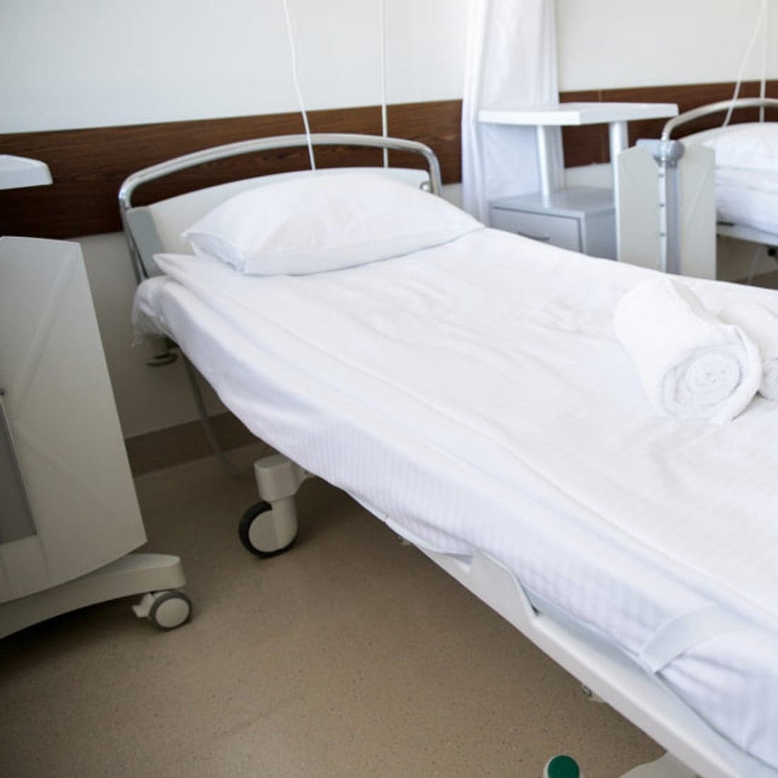 A made hospital bed with a rolled towel