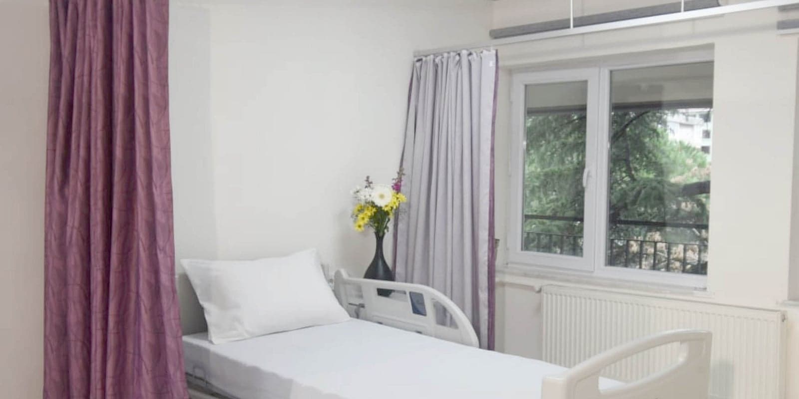 A hospital bed with privacy curtains and white linen