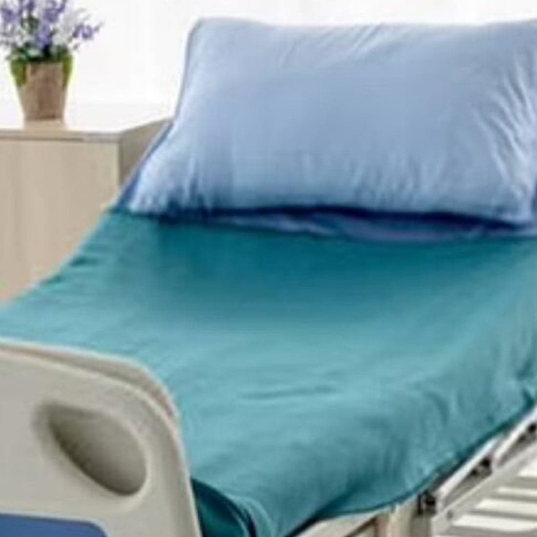 A hospital bed in teal draw-sheet linen