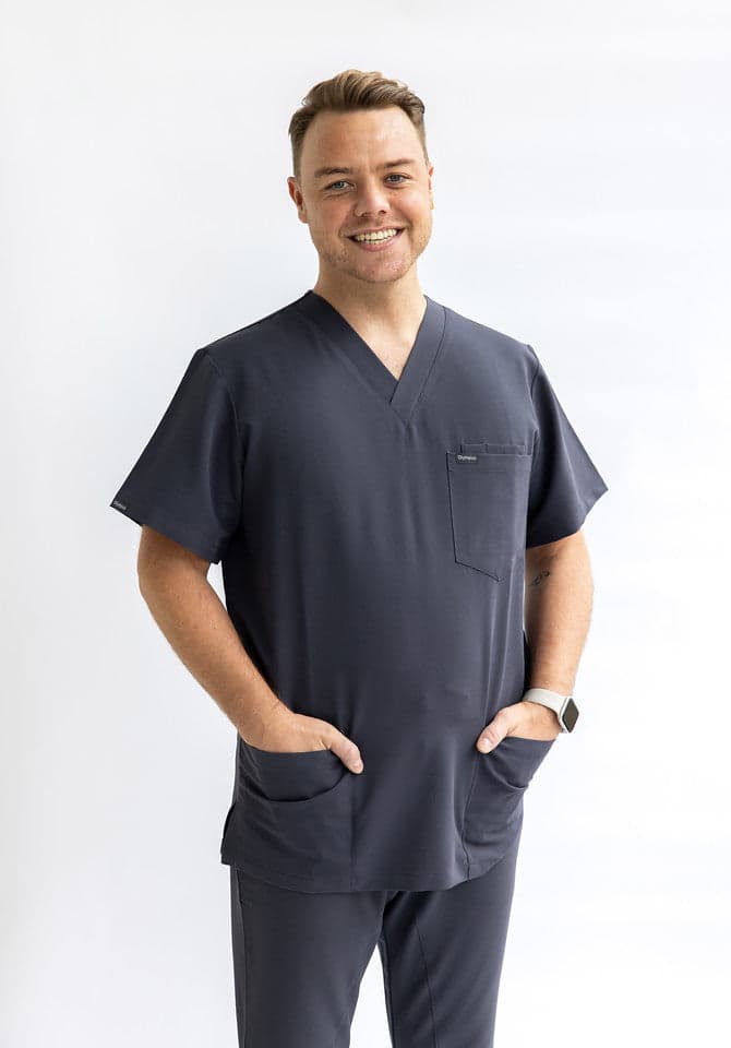 A charcoal theatre scrub top worn by a clinician