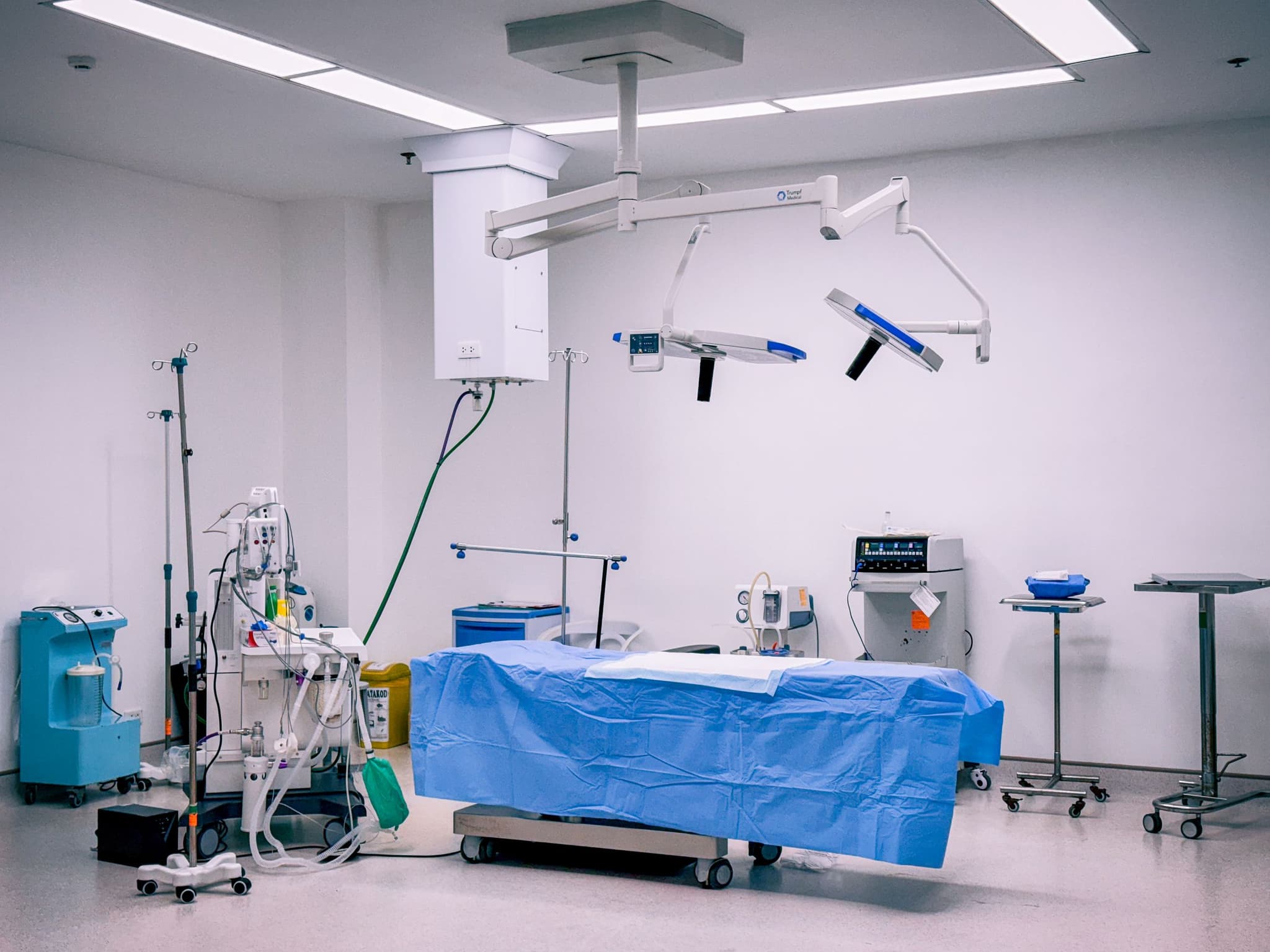 A bright, clean operating theatre with a blue sterile drape over the table