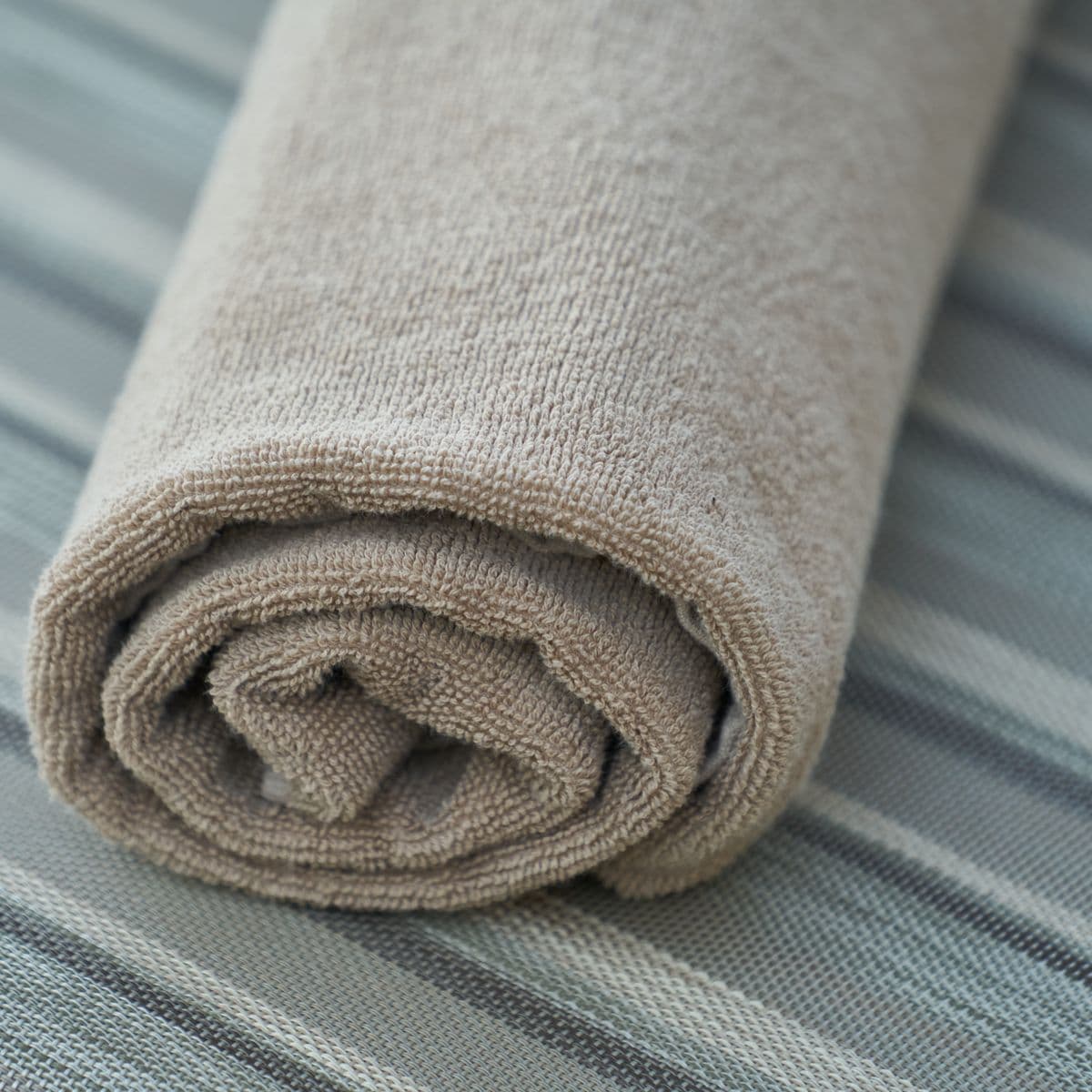 A single rolled stone-grey towel