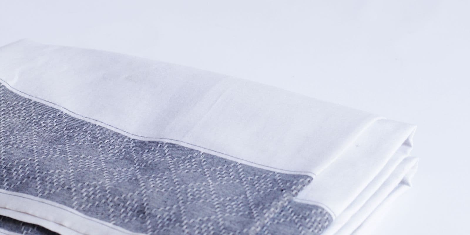 A folded white cloth with a grey woven border