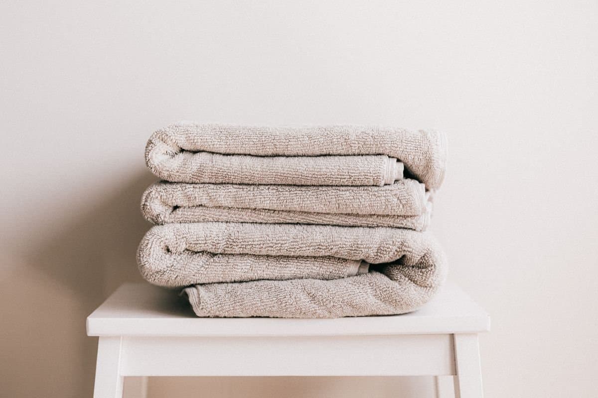 Folded neutral cotton towels on a stool