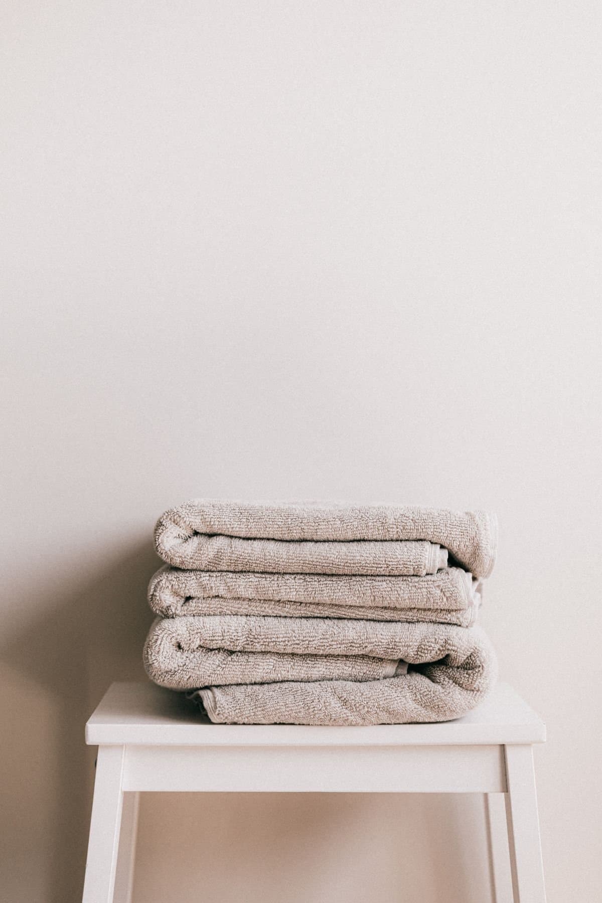 Folded neutral cotton towels on a stool