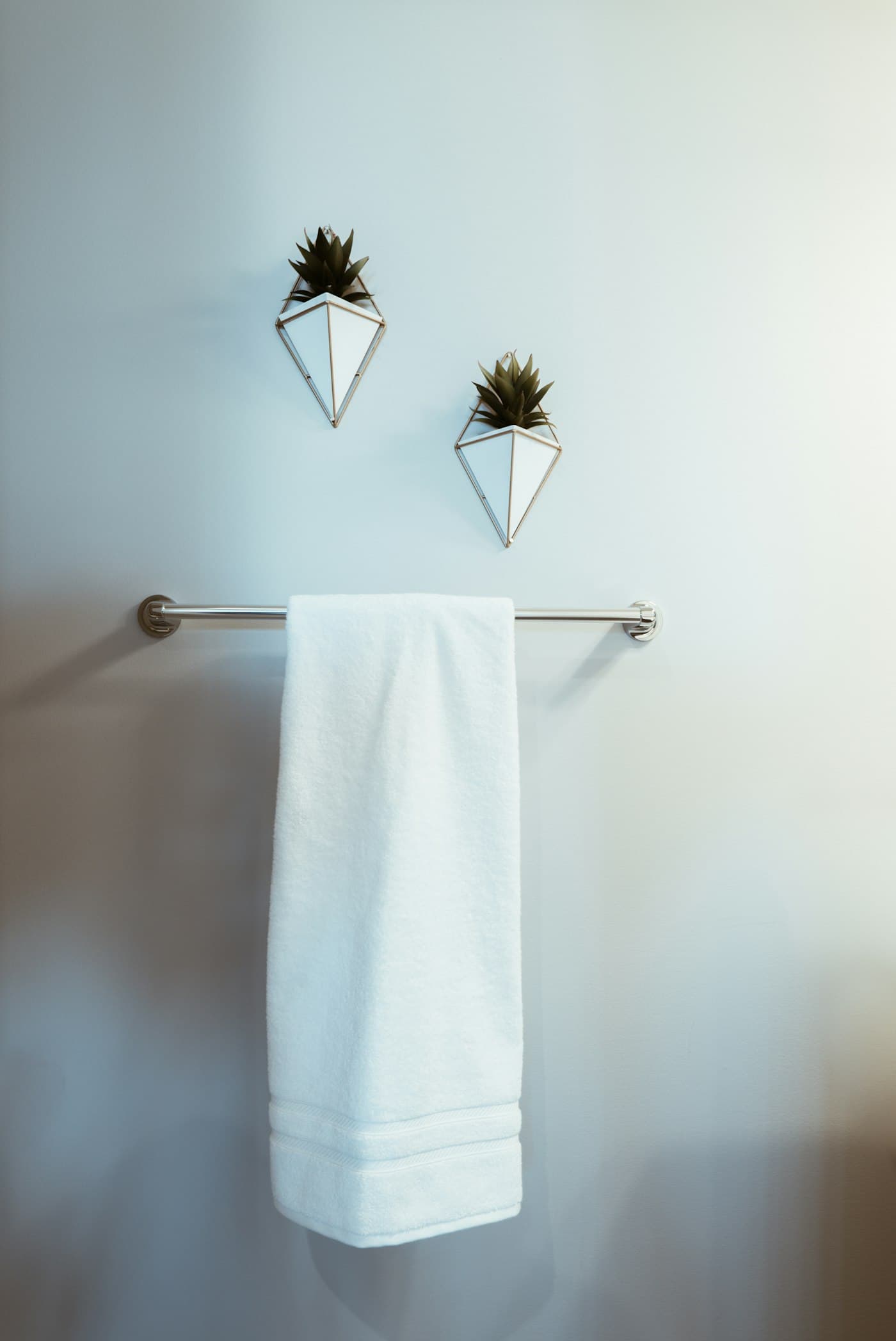 A white hand towel hung on a chrome rail