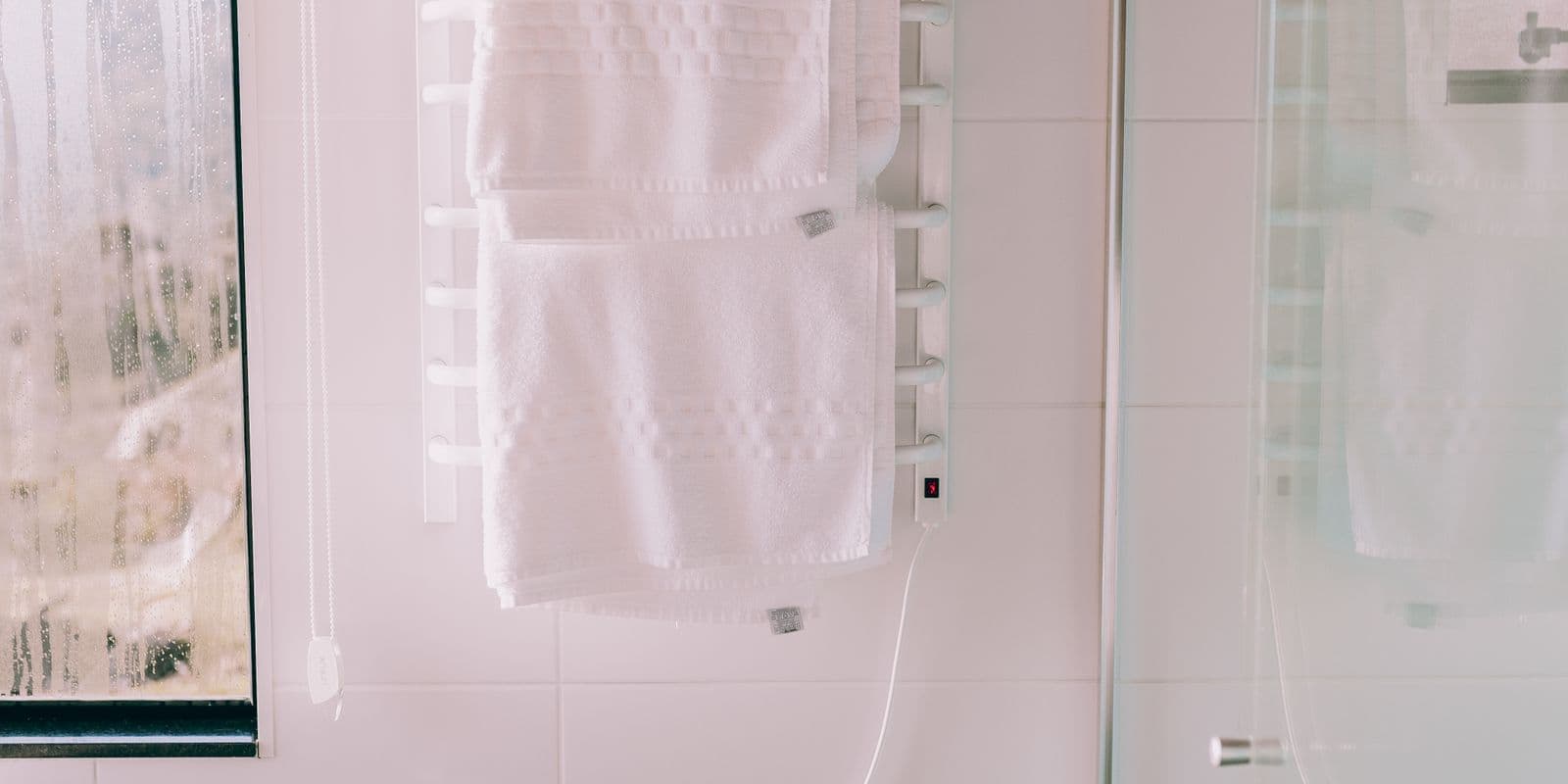 Crisp white towels on a heated rail in a bright clean bathroom