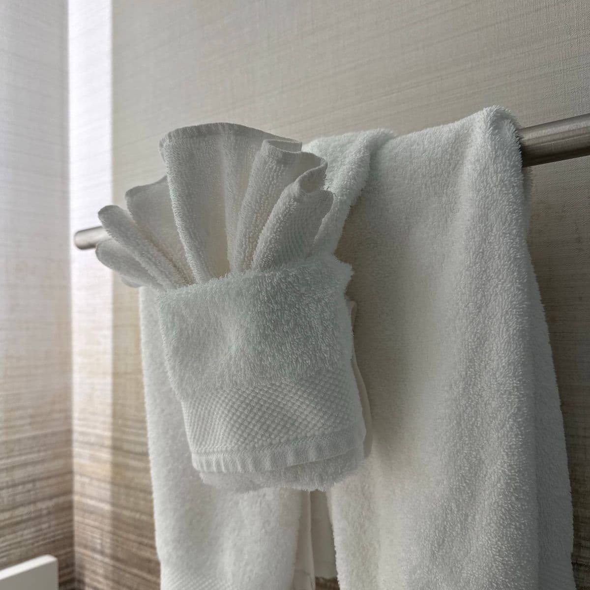 Soft white towels styled on a rail against a light wall