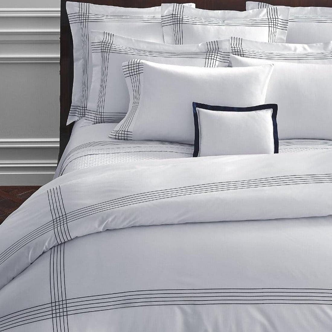 Pintuck-detailed white pillows on layered bedding