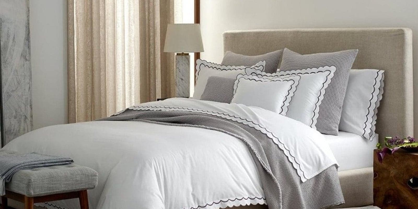 A made-up bed dressed in soft white bedding in a bright styled bedroom