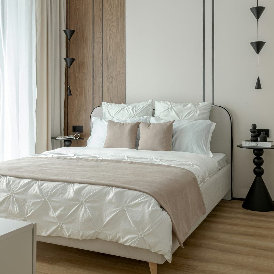 A bed made up with a white duvet and soft beige pillow beside a wooden nightstand